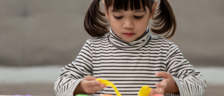 A child with pigtails plays with a toy.