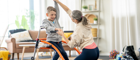 A therapist helps a child using assistive equipment