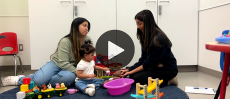 A mother and child play on the floor with the Speech Language Pathologist