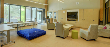 A photo of a lounge with a beanbag mat, lounge chairs and tv.