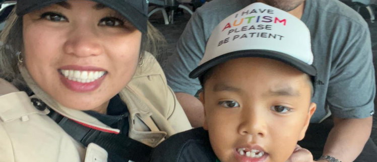 Isaac and his mother. Isaac wears a hat that reads I have autism, please be patient