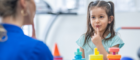 A child imitates her clinician by putting her finger to her mouth