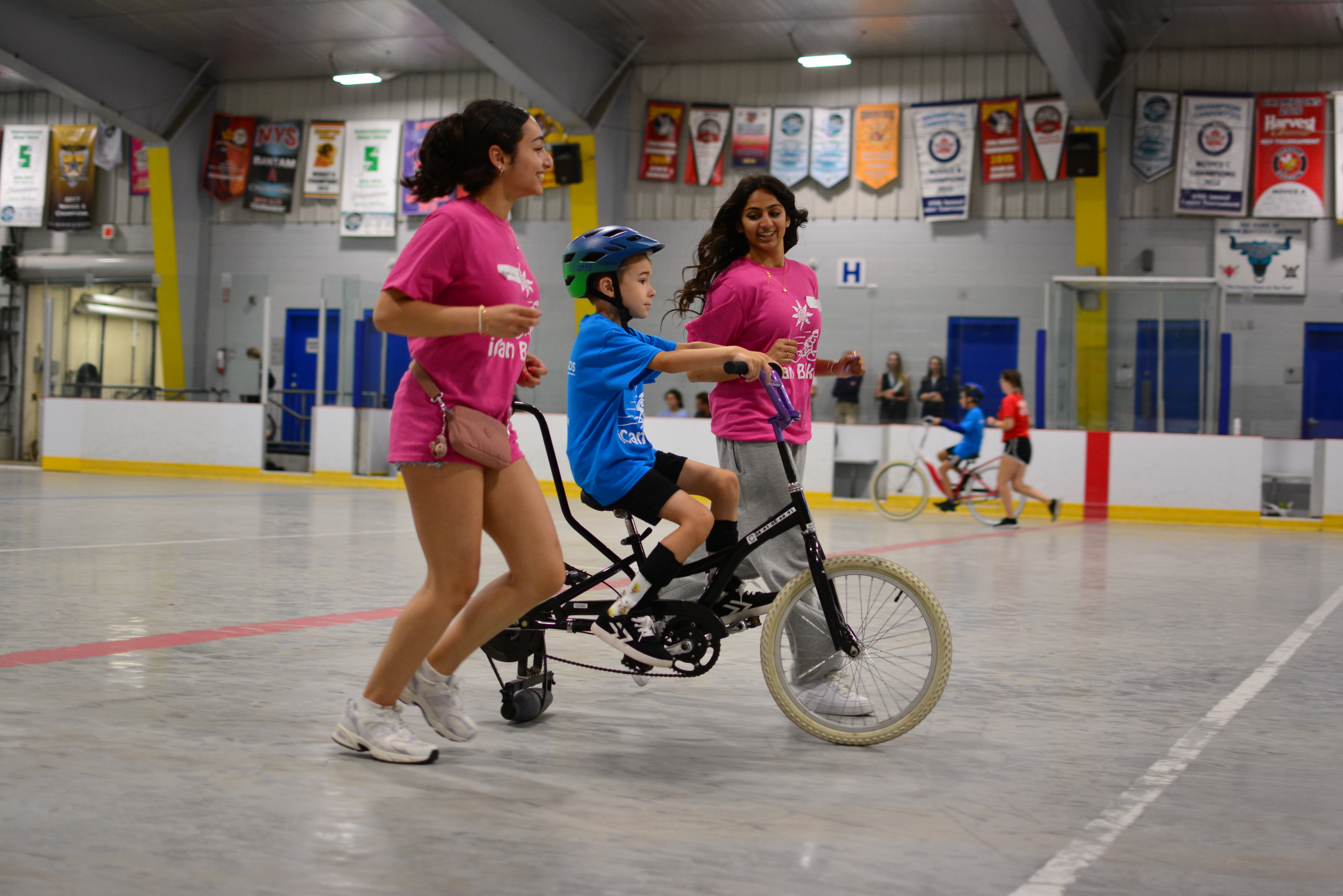 volunteers assist a student with riding a bike