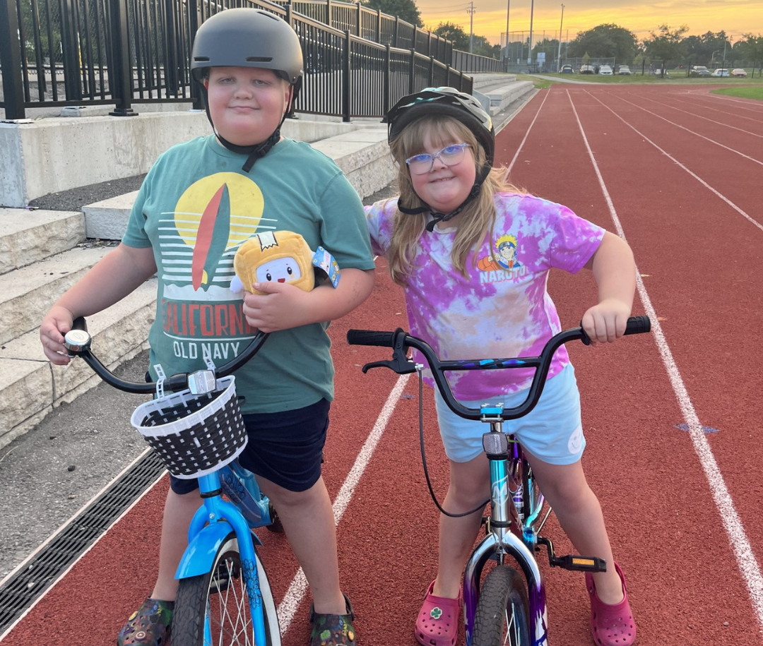 Gavin and his sister riding their bikes on a track