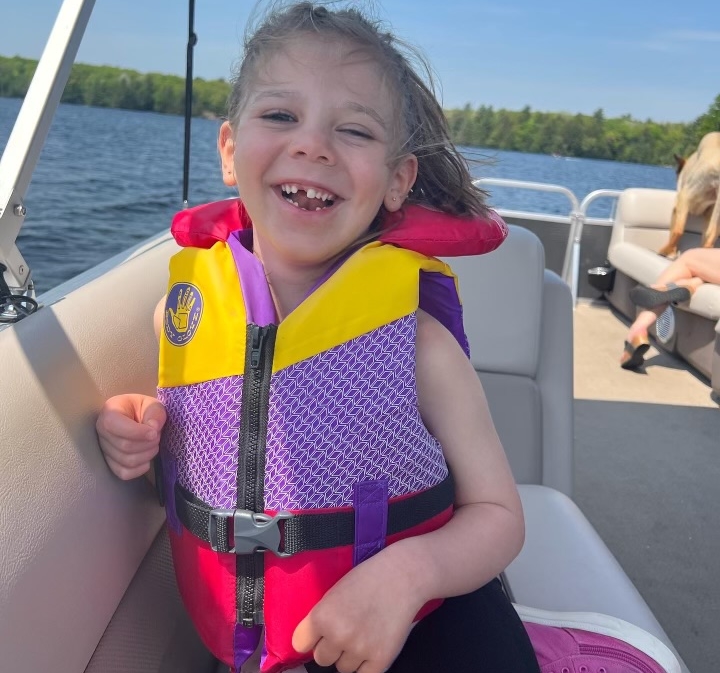 Mikayla smiles brightly in a boat wearing a life jacket.