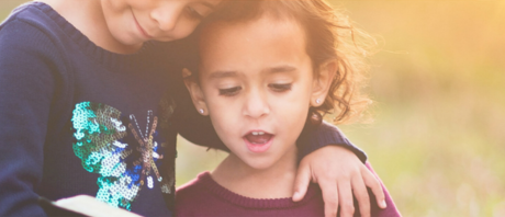 An older sibling wraps her arm around her younger sister