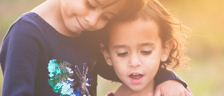 young girl talks while older sister listens