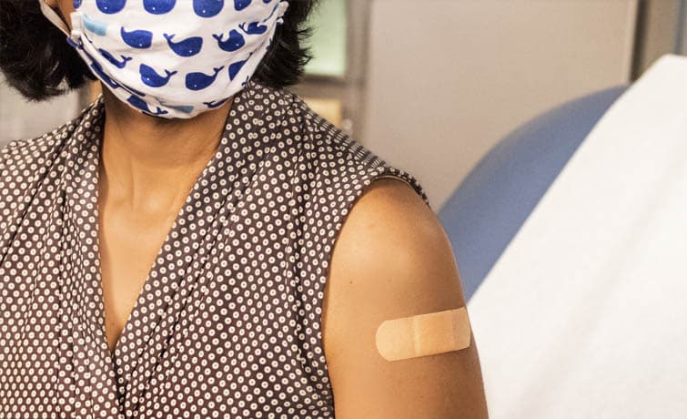 woman wearing mask with bandaid on her arm