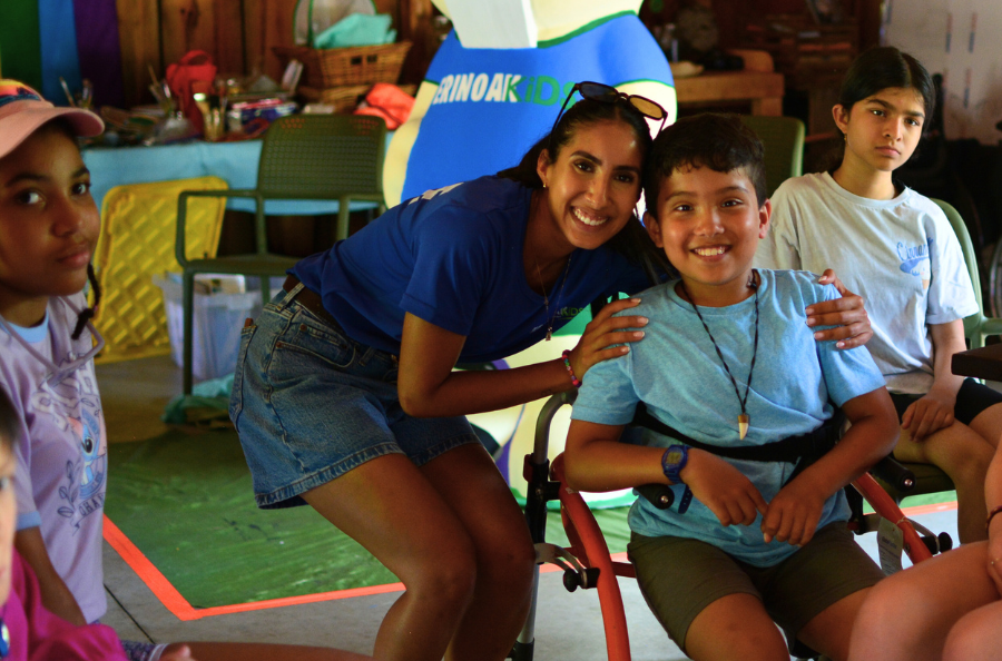 A woman wearing an ErinoakKids lanyard assists a young boy in decorating a cupcake