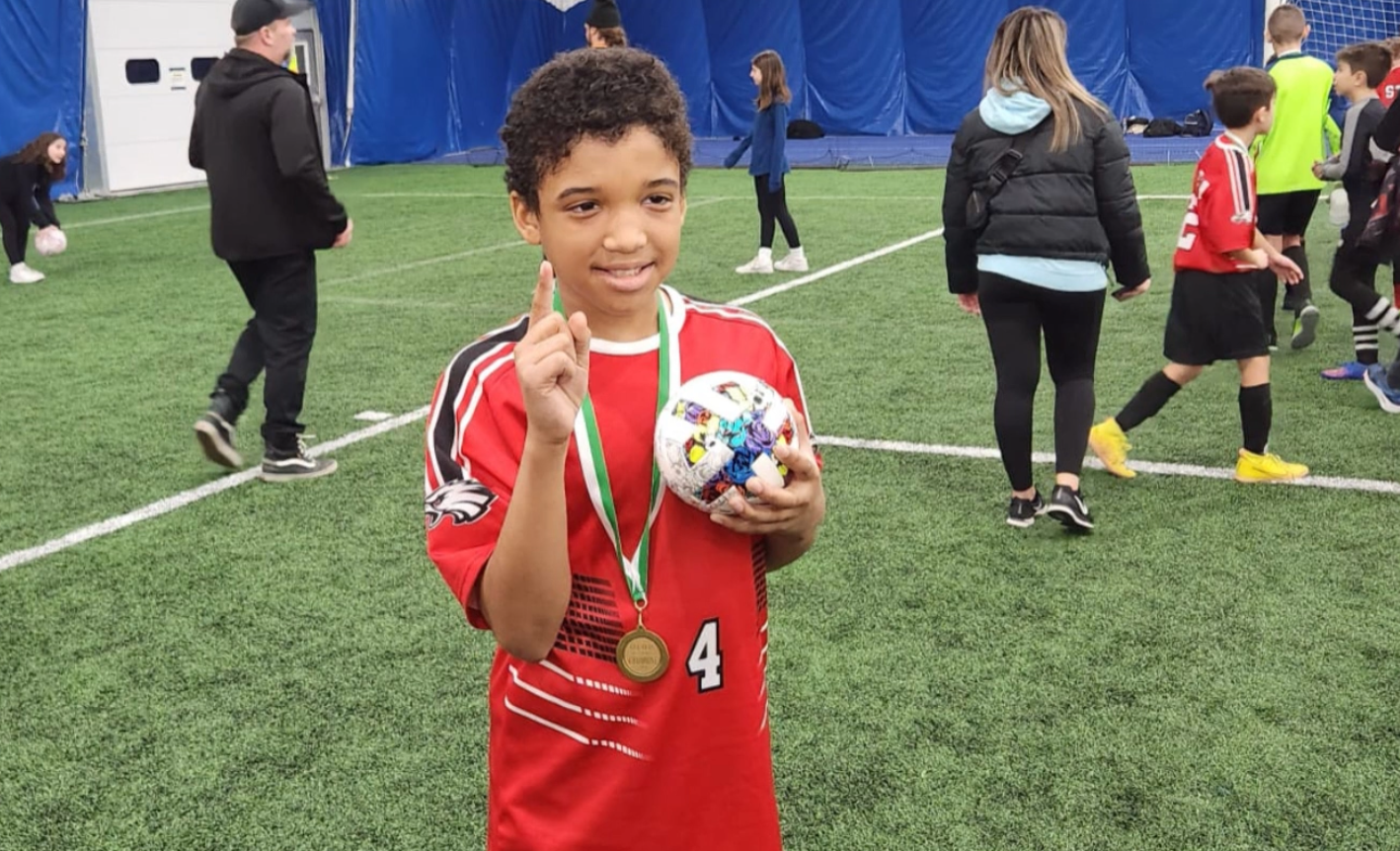 Jaisen wearing a metal and holding a soccer ball