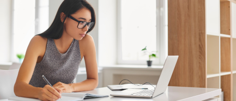 Person on a laptop while writing down notes